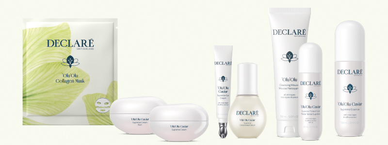 Pflegeserie von Declaré Switzerland aus der Olu’Olu Caviar Linie: Collagen-Maske, Cremes, Serum, Reinigung und Essenz in weißen Verpackungen mit blauer Aufschrift, vor hellem Hintergrund angeordnet.