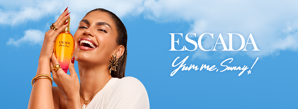 Werbebanner für das Parfum „Yum Me Sunny“ von ESCADA: Lachendes Model mit goldenen Schmuckaccessoires hält einen orange-pinkfarbenen Duftflakon vor blauem Himmel; rechts steht der Schriftzug „ESCADA Yum Me Sunny!“.