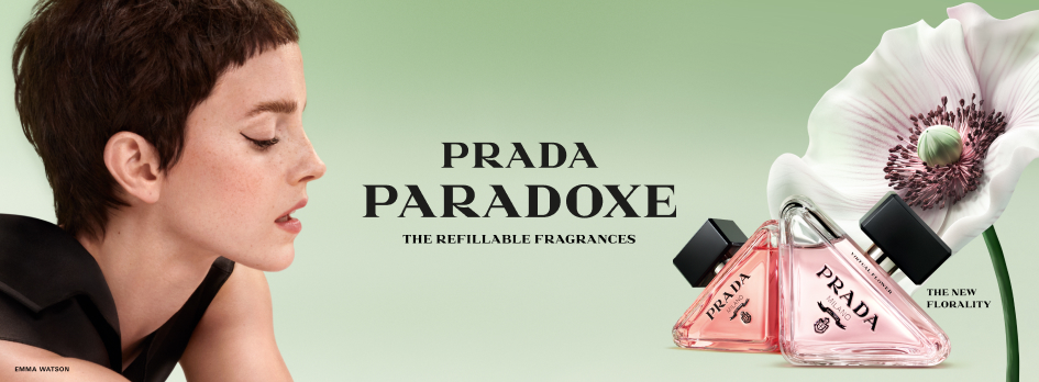 Werbung für das Parfum 'Prada Paradoxe': Links ist Schauspielerin Emma Watson im Profil mit kurzem Haar und geschlossenem Mund zu sehen. In der Mitte steht der Schriftzug 'Prada Paradoxe – The Refillable Fragrances'. Rechts im Bild zwei dreieckige rosa Parfumflakons neben einer großen, weißen Blüte mit dunkler Mitte. Text: 'The New Florality'.